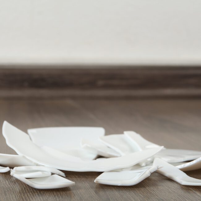 Pieces,Of,Broken,Ceramic,Plate,On,Wooden,Floor,Indoors,,Space